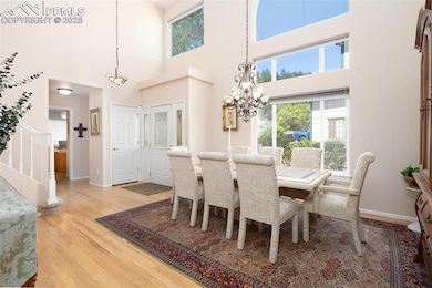 Dining area featuring light wood-style floors, stairway, a chandelier, a towering ceiling, and baseboards