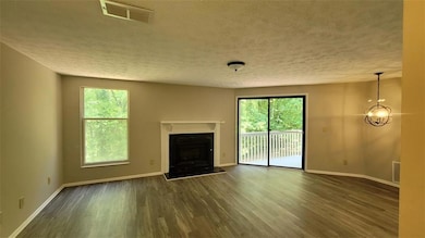 Unfurnished living room with dark wood-style flooring, a fireplace, and a textured ceiling