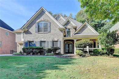 View of front facade with brick siding, a front yard, and a porch