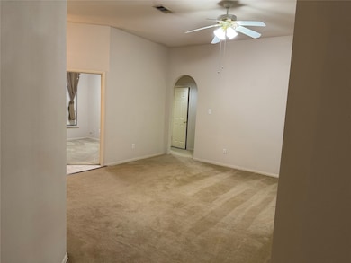 Unfurnished room featuring light colored carpet, arched walkways, and a ceiling fan