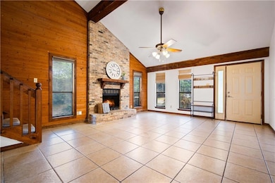 Unfurnished living room with healthy amount of natural light, wooden walls, light tile patterned floors, stairs, and high vaulted ceiling