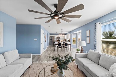Living room featuring light wood finished floors, a ceiling fan, and a chandelier