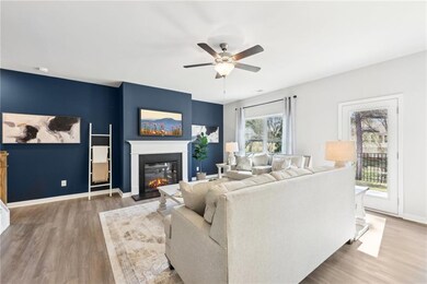 Living room with wood finished floors, ceiling fan, a glass covered fireplace, and baseboards