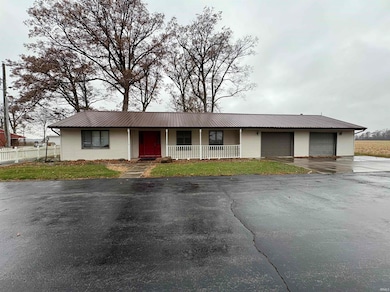 Single story home featuring driveway, a porch, a metal roof, and a front yard