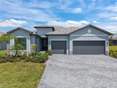View of front facade with decorative driveway, a garage, stone siding, stucco siding, and a front lawn
