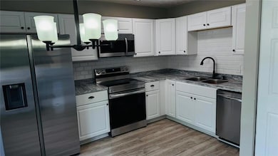 Kitchen featuring a sink, appliances with stainless steel finishes, white cabinets, and tasteful backsplash