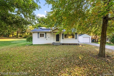 View of front of home featuring roof mounted solar panels, a front lawn, a garage, and driveway