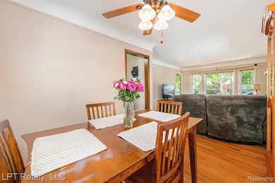Dining area featuring light wood-type flooring, ceiling fan, and crown molding