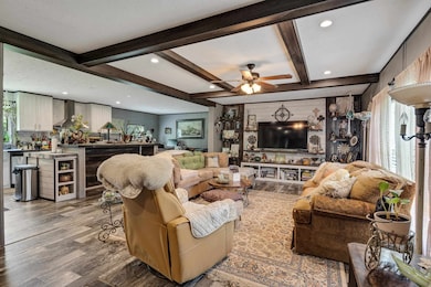 Living room featuring wood finished floors, ceiling fan, beam ceiling, recessed lighting, and bar