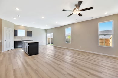 Kitchen with a kitchen island, open floor plan, dark cabinets, recessed lighting, and light wood finished floors