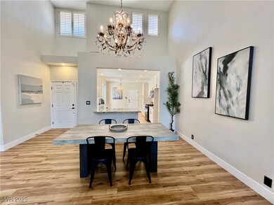 Dining area featuring a chandelier, a towering ceiling, and light wood-style flooring