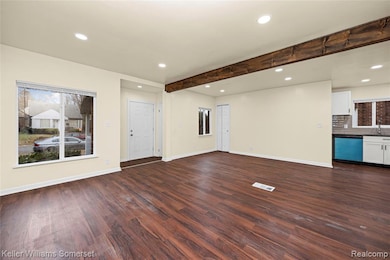 Unfurnished living room with recessed lighting, beam ceiling, and dark wood-type flooring