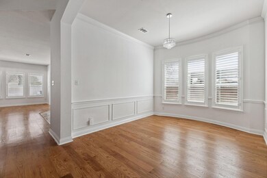 Entrance to see formal dining room featuring ornamental molding, a chandelier, a wealth of natural light, and light wood-type flooring