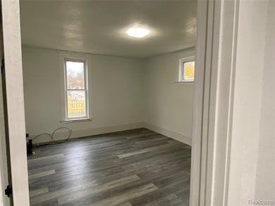 Empty room with dark wood-type flooring and a textured ceiling