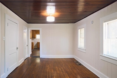 Unfurnished room featuring dark wood finished floors, wood walls, and wooden ceiling