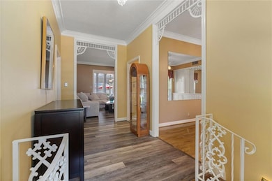 Hallway with dark wood-style flooring, crown molding, arched walkways, and a textured ceiling