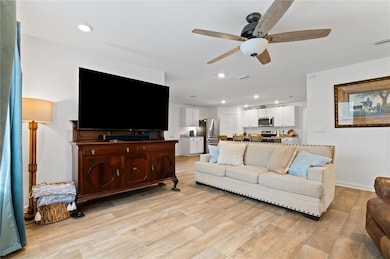 Living room featuring ceiling fan and light wood-t