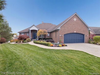 View of front of house with a front lawn, driveway, brick siding, and an attached garage