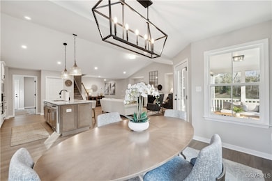 Dining space featuring stairs, lofted ceiling, woo