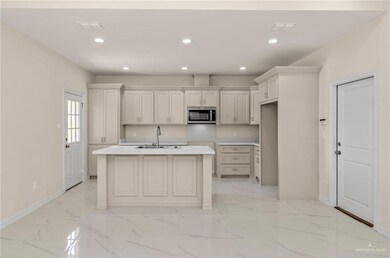 Kitchen featuring sink, a kitchen island with sink, and white cabinets