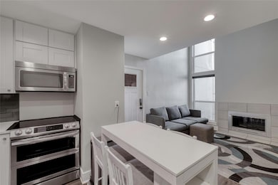 Kitchen with white cabinets, a tile fireplace, li