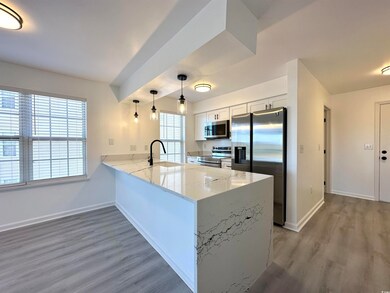 Kitchen with appliances with stainless steel finishes, baseboards, a peninsula, and light wood finished floors