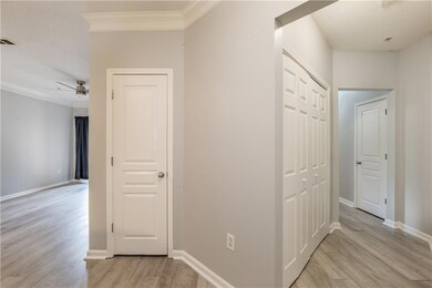 Corridor with light wood-type flooring, crown molding, and a textured ceiling