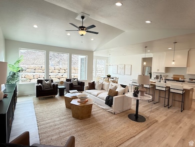 Living room with light wood-type flooring, vaulted ceiling, a textured ceiling, and recessed lighting