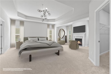 Bedroom with a tray ceiling, carpet flooring, a chandelier, a premium fireplace, and baseboards