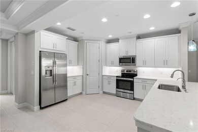 Kitchen with stainless steel appliances, a sink, ornamental molding, backsplash, and white cabinets