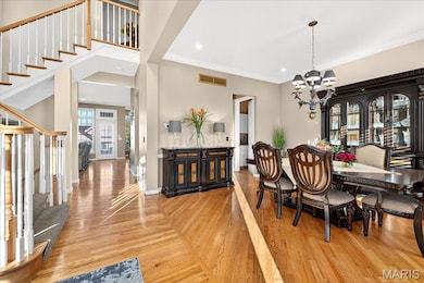 Dining room with stairs, light wood-style flooring, a chandelier, ornamental molding, and recessed lighting