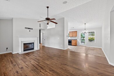 Unfurnished living room with wood finished floors, a premium fireplace, a ceiling fan, a chandelier, and a textured ceiling