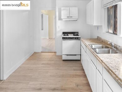 Kitchen featuring white cabinets, light wood-style flooring, white range with gas cooktop, light countertops, and under cabinet range hood