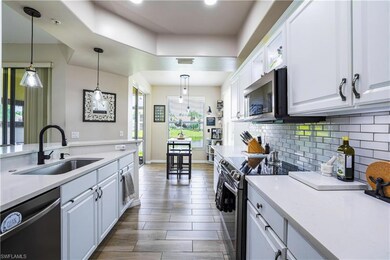 Kitchen with appliances with stainless steel finishes, tasteful backsplash, white cabinets, and light countertops