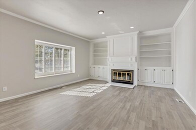 Unfurnished living room featuring built in features, crown molding, a fireplace, light wood-type flooring, and recessed lighting
