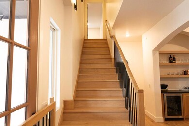 Staircase featuring beverage cooler, bar area, plenty of natural light, and wood finished floors
