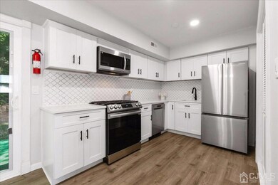 COMPLETELY renovated kitchen featuring a beautiful backsplash, stainless steel appliances and quartz counters