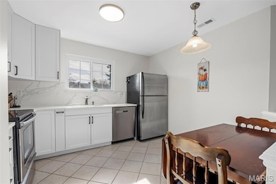 Kitchen with appliances with stainless steel finishes, decorative backsplash, white cabinets, and light tile patterned floors