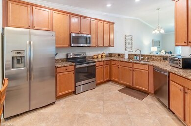 Kitchen featuring hanging light fixtures, stainless steel appliances, sink, vaulted ceiling, and an inviting chandelier