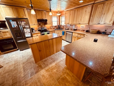 Kitchen with wood ceiling, stainless steel appliances, stone countertops, a kitchen island, and light brown cabinets
