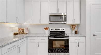 Kitchen featuring white cabinetry, stainless steel