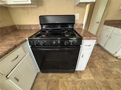 Kitchen with black gas range, white cabinetry, and dark countertops