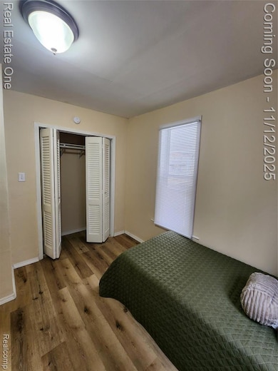 Bedroom with wood finished floors and a closet