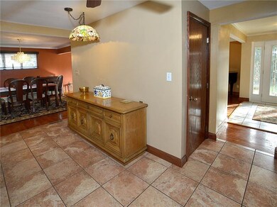 Standing in front of the kitchen cabinets, you can see the dining room as well as the spacious entry.