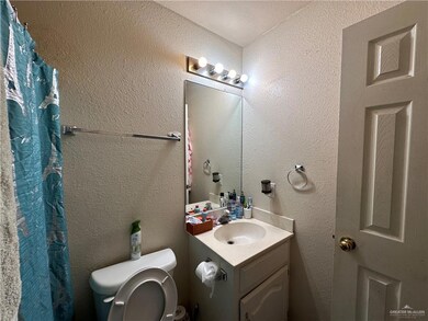 Bathroom with curtained shower, toilet, and vanity