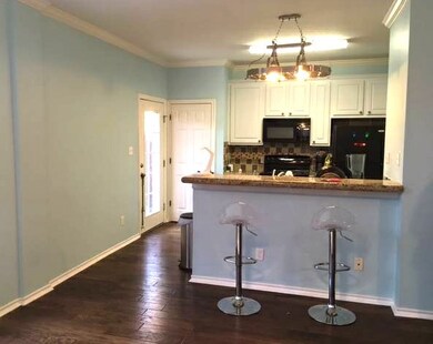 Kitchen featuring ornamental molding, tasteful backsplash, a kitchen bar, dark wood-style floors, and black appliances