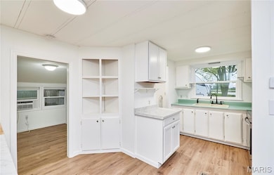 Kitchen with white cabinets, light countertops, open shelves, light wood-style flooring, and stainless steel electric range