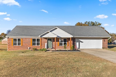 Ranch-style home featuring concrete driveway, a shingled roof, and brick siding