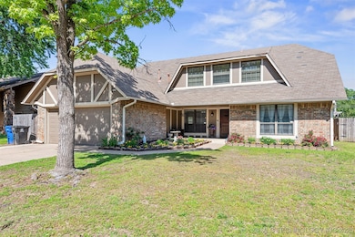 Tudor home with brick siding, garage, and front ya