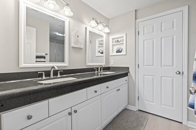 Full bathroom with double vanity, a sink, baseboar